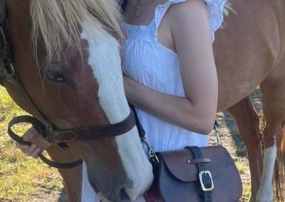 Girl in white dress with horse and vintage leather bag